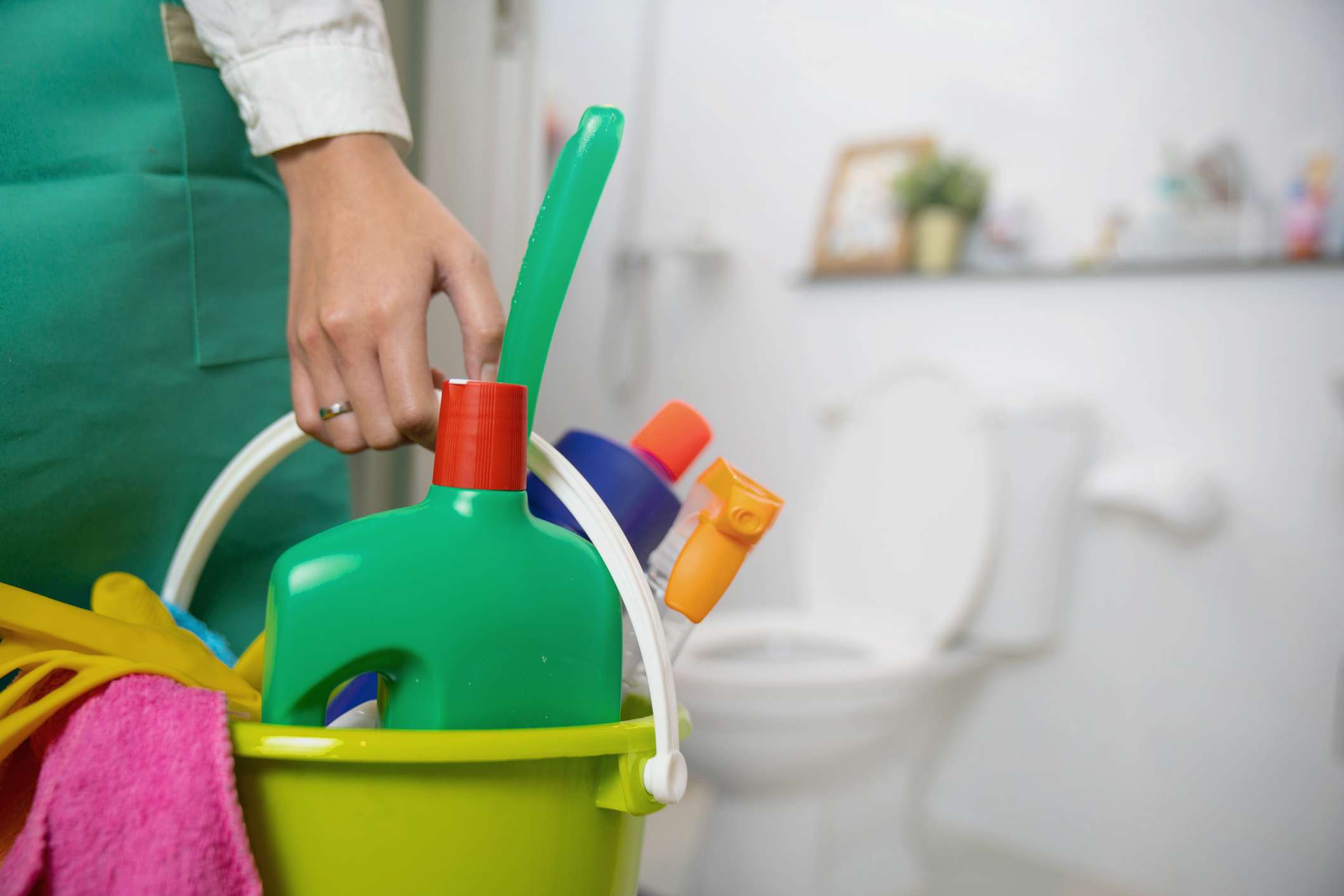 The cleaning woman is standing in the bathroom holding a blue bucket full of chemicals and facilities for storing her hands. Cleaning Toilet