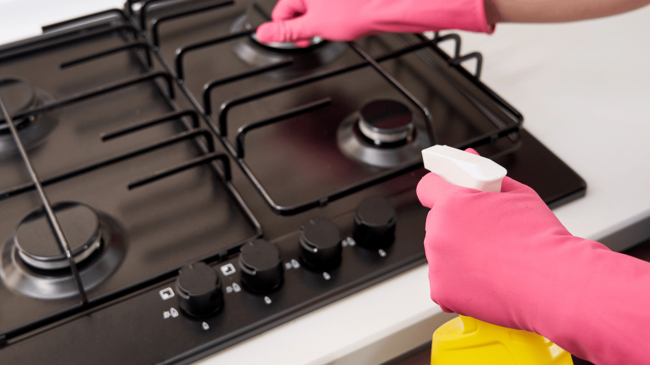 A woman using a rag to clean both inside and outside of the oven.