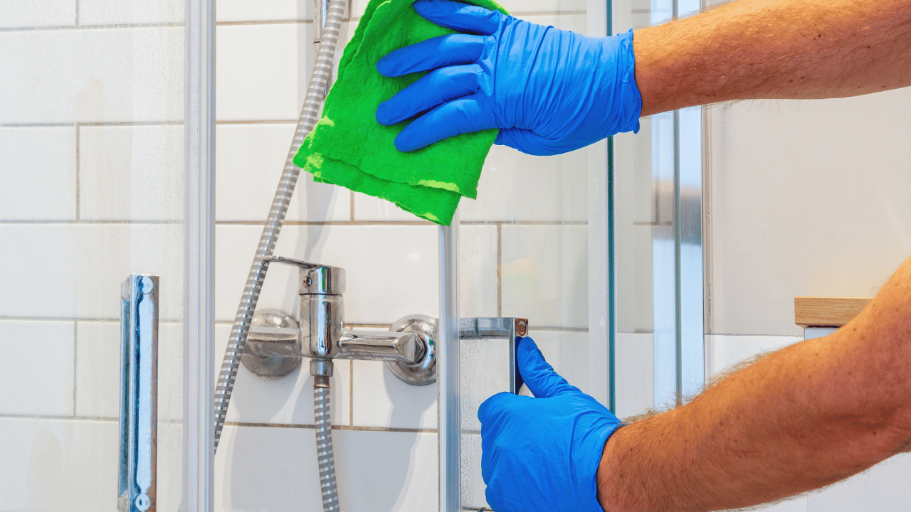 A woman using a rag to clean both inside and outside of the oven.