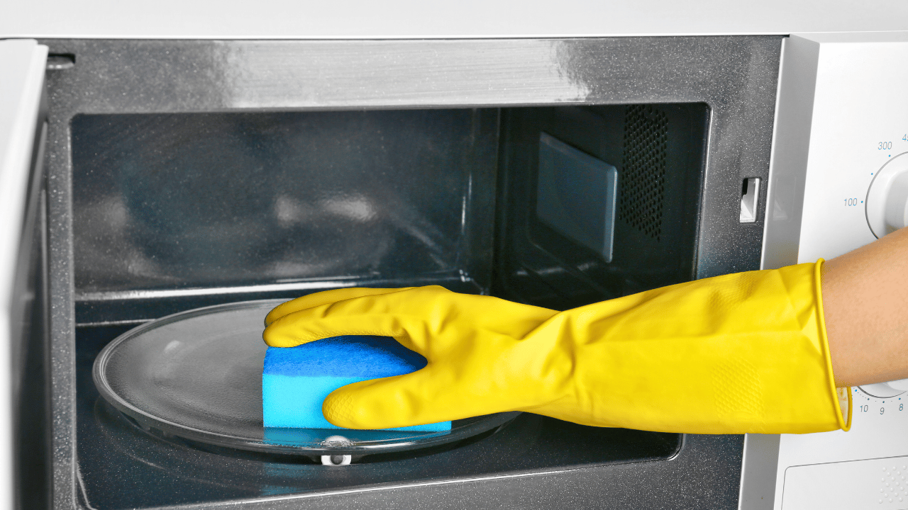 A woman using a rag to clean both inside and outside of the oven.